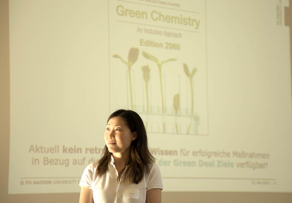 Professorin Yi Zhang im Profil. Im Hintergrund ist ene Folie aus ihrer Präsentation zu sehen. Darauf steht "Green Chemistry".